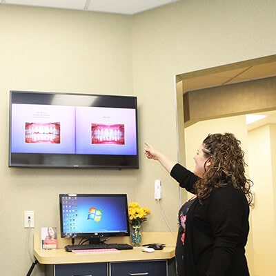 Our team member in the office pointing at a monitor that shows images of teeth