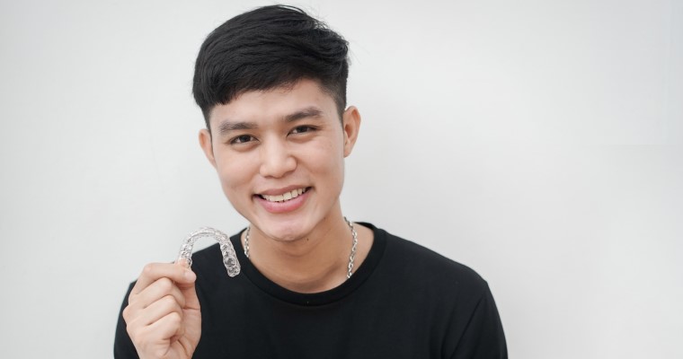 Male smiling holding an Invisalign tray
